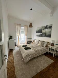 a white bedroom with a bed and a table at Casa do Avô in Sacavém