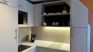 a kitchen with white cabinets and a sink at Heeton Concept Aparthotel Edinburgh Queen Street in Edinburgh +34 photos