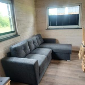 a living room with a couch and two windows at Łąkowe Wzgórze in Kosewko
