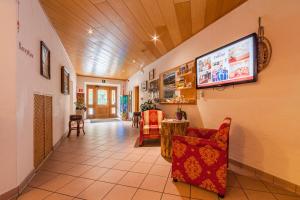 a hallway with chairs and a tv on the wall at Hotel Tolderhof in San Candido