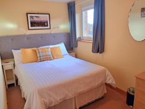 a bedroom with a bed and a window and a mirror at Roe Deer Cottage in Beauly