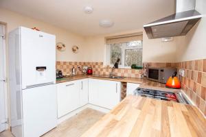 a kitchen with white cabinets and a white refrigerator at Roe Deer Cottage in Beauly