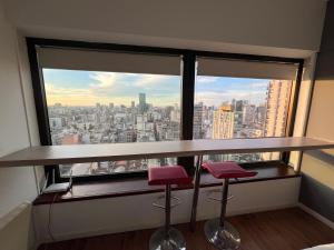 a bar with two stools in front of a large window at Apart hotel Ciudad de Bs As in Buenos Aires