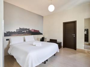 a bedroom with a large white bed with a painting on the wall at B&B Hotel Napoli in Naples