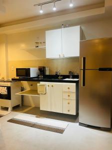 a kitchen with a stainless steel refrigerator and white cabinets at Apartamento moderno no Centro de Cabo Frio in Cabo Frio