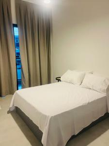 a white bed in a room with a window at Apartamento moderno no Centro de Cabo Frio in Cabo Frio