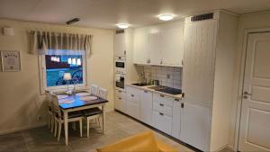 a kitchen with white cabinets and a table and a window at Lillstugan i Rasbo in Uppsala