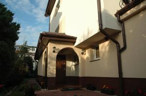 a white building with an archway and a door at Dom Gościnny Korab in Kołobrzeg