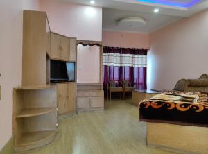a bedroom with a bed and a flat screen tv at Hotel Hari mangalam heritage in Tehri-Garhwāl