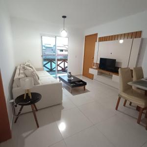 a living room with a white couch and a table at Village - Cond Planeta Água - Jacuípe in Barra de Jacuípe