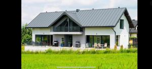a white house with a metal roof at Domki pod Lasem 66 in Trybsz