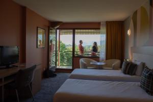 a hotel room with two beds and a balcony at Hotel *** & Spa Vacances Bleues Villa Marlioz in Aix-les-Bains