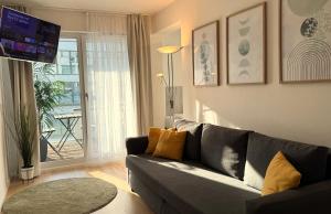 a living room with a gray couch and a balcony at DUTTI'S HOME - 1 Zimmer Apartment, Küche, Self-Check-in, Stellplatz in Ingolstadt