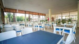 ein Restaurant mit blauen Tischen, weißen Stühlen und Fenstern in der Unterkunft CASTLE PARK HOTEL in Beldibi