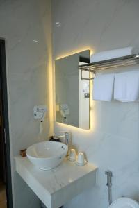 a white bathroom with a sink and a mirror at Som Phu Quy 3 Hotel Phan Rang in Phan Rang–Tháp Chàm +33 photos