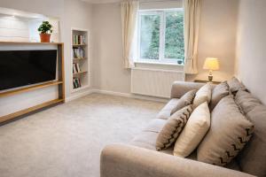 a living room with a couch and a television at Fernhill Hideaway in Charmouth +7 photos