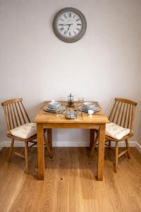 a wooden table with two chairs and a clock on the wall at Fernhill Hideaway in Charmouth