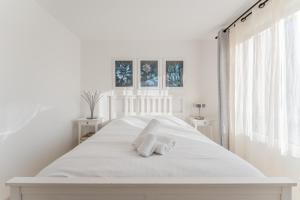 a white bedroom with a large white bed with two towels at Dumbo - Île de Nantes in Nantes