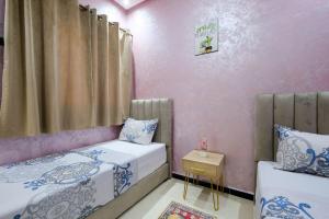 two beds in a room with pink walls at Riad Bollywood-Golden Stay D in Benguerir