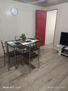 a dining room table with chairs and a clock on the wall at Casa en arriendo in Quintero