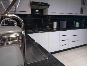 a kitchen with white cabinets and a sink at Joyful Home Bela-Bela in Bela-Bela +65 photos