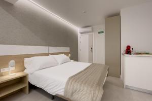 a bedroom with a large white bed and a table at 6 de Mayo alojamientos in Almansa