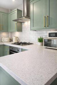 a kitchen with green cabinets and a white counter top at The Distillery Room in Scarborough