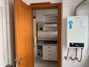 a small kitchen with a stove and a refrigerator at Apartamento junto mar, bem ventilado e iluminado - Antilhas 679 in Capão da Canoa