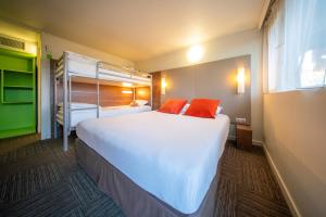 a bedroom with a large white bed with two orange pillows at Brit hôtel confort Ampaline Périgueux est in Boulazac