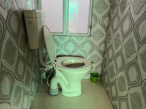 a bathroom with a toilet and a window at Krishna guest house in Sāmbhar