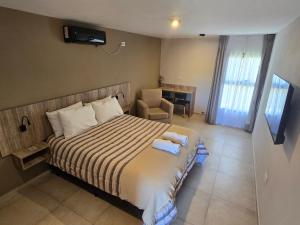 a bedroom with a bed with a chair and a desk at La Finca hotel in Cruz del Eje +31 photos