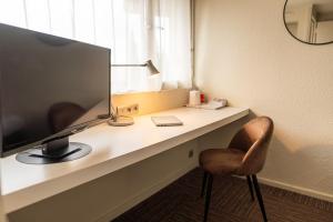 a desk with a television and a chair and a lamp at Brit hôtel confort Ampaline Périgueux est in Boulazac