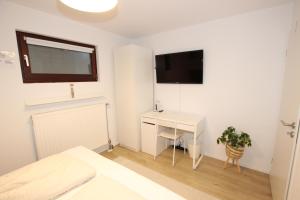 a white bedroom with a desk and a television at Gemütliches Schwarzwald-Apartment im ruhigen Untergeschoss eines Hauses in Denzlingen