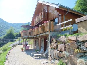 a log house with a balcony and a stone wall at Appartement vue panoramique in Binos