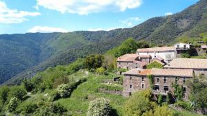 a village on a hill with mountains in the background at Le Châtaignier in Faveyrolles