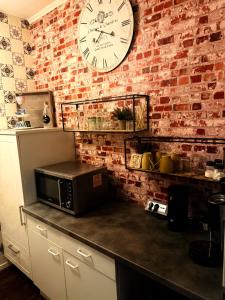 a clock on a brick wall with a microwave on a counter at Ferienwohnung Time out in Vreden