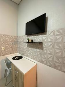 a room with a tv on a wall with a chair at Refugio Aconchegante2 in Nova Mutum