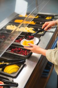 a woman is reaching for a plate of food at McIntosh Hall - Campus Accommodation in St. Andrews