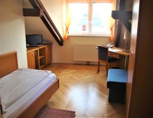 a small bedroom with a bed and a desk and a window at Gästehaus Einzinger in Krems an der Donau