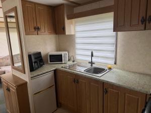 a small kitchen with a sink and a microwave at T & L CARAVANs in Skegness +19 photos