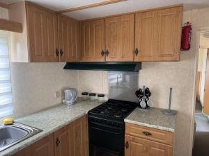 a kitchen with wooden cabinets and a stove and a sink at T & L CARAVANs in Skegness