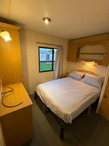 a bedroom with a large bed and a window at T & L CARAVANs in Skegness