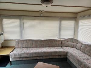 a couch in a living room with windows at T & L CARAVANs in Skegness