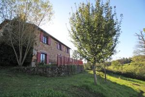 a stone house with a tree in front of it at Leygat in Solignac