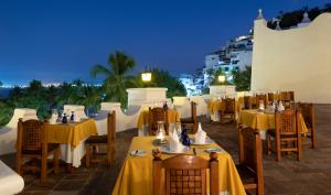 a restaurant with yellow tables and chairs at night at Las Hadas by Brisas in Manzanillo
