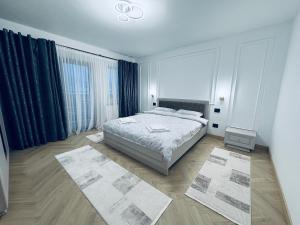 a white bedroom with a bed and two rugs at Casa Pop in Petrova