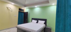 a bedroom with a large bed with green walls at Hanumant Dham in Dārāganj +8 photos