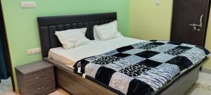 a bedroom with a bed with a black and white quilt at Hanumant Dham in Dārāganj