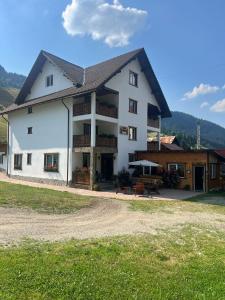 a white house with a gambrel roof at Casa Rares in Moieciu de Sus