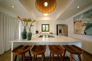 a kitchen with a island with four chairs and a counter at Elegant Villa with Poolfront View in Monterrico